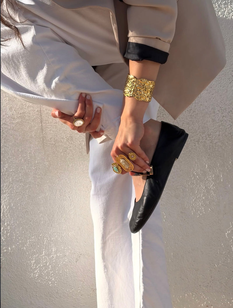 Brazalete y anillos dorados Bolatil con un look blanco